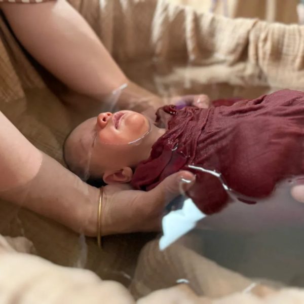 Bain enveloppé du nouveau-né, bébé lové dans un lange au creux de l’eau