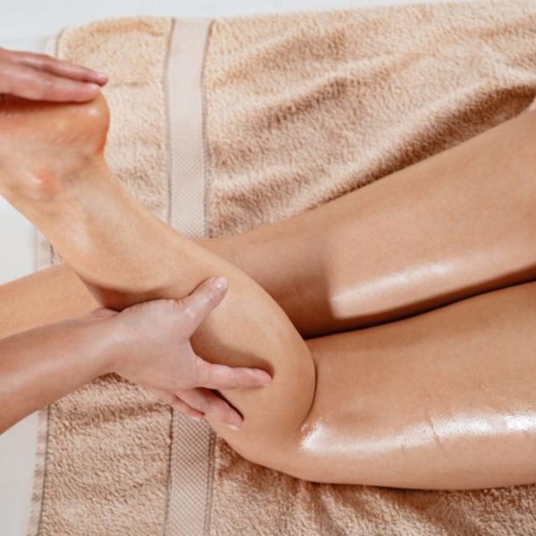 Massage à l'huile des jambes, gestes enveloppants de la praticienne