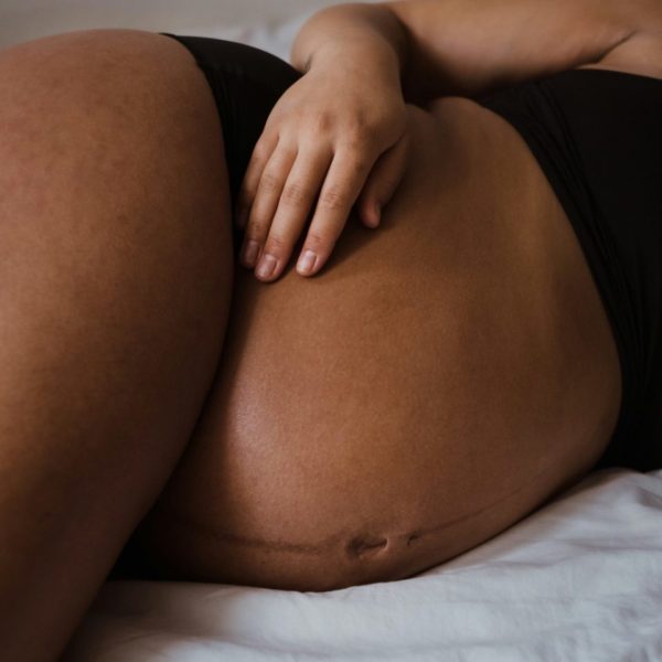 Ventre d'une femme enceinte allongée, ses mains posées sur son ventre
